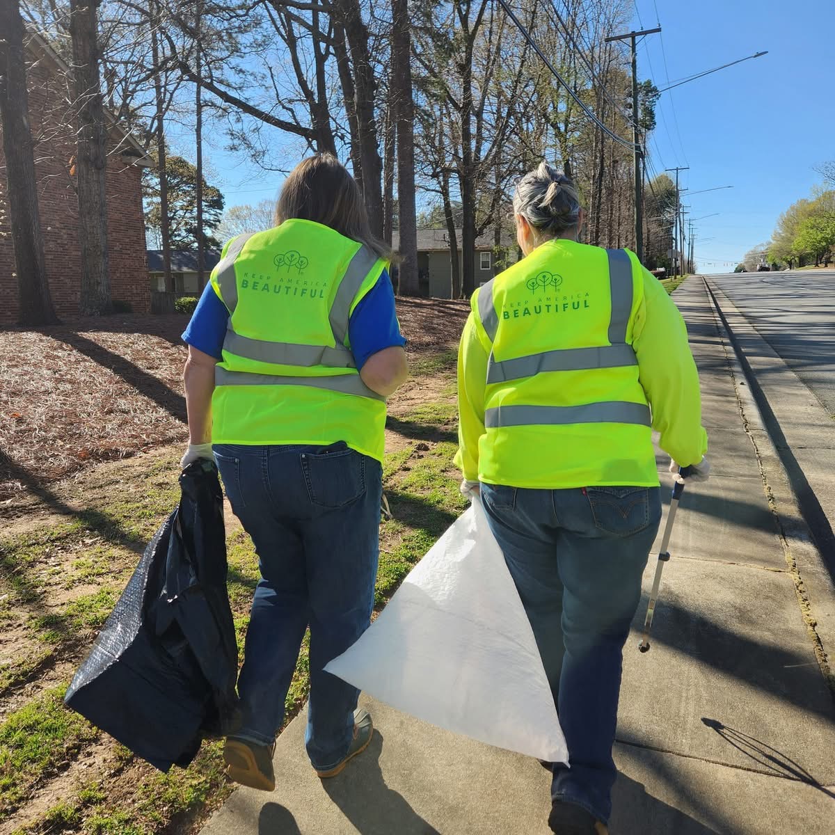 Two volunteers walking with trash bags
